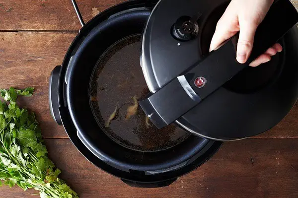 Holding a lid above a pressure cooker.