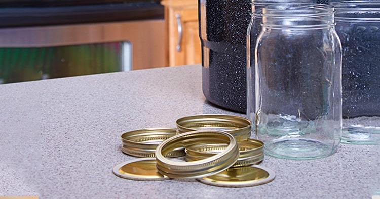 Canning jars with lids, canner or pot in a kitchen setting