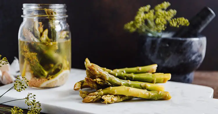 Pickled asparagus on a white marble tray