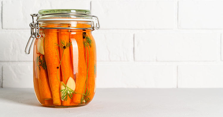 Homemade fermented carrots with garlic, dill and pepper in a glass jar.