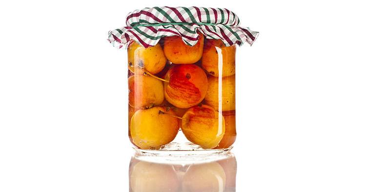 Apples in glass jar close up isolated on a white background