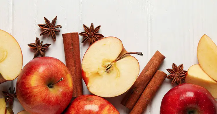 Apples and cinnamon on wooden background, space for tex