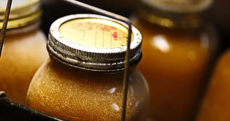 Golden applesauce preserved in glass mason jar. Canning process in hot water bath on small homestead.