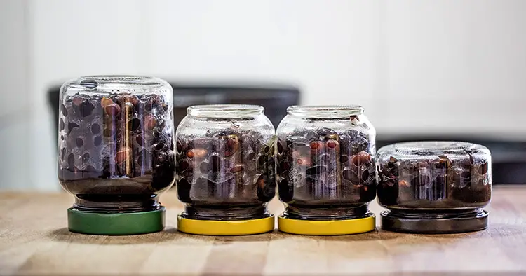 Preserved food in glass jars on wood. Handmade black beans, simmered with sugar and soy sauce.