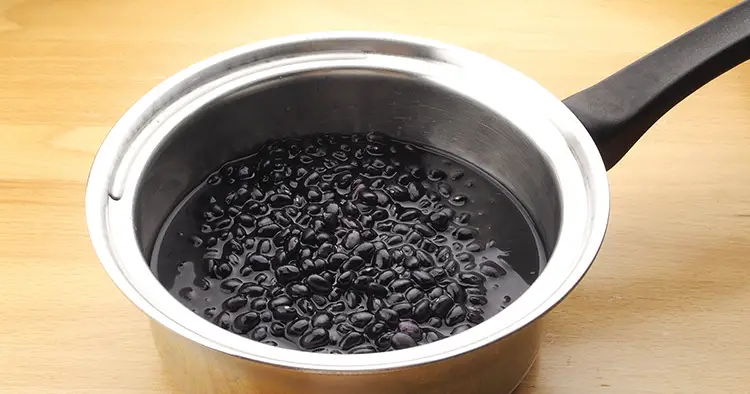 Stainless steel pot with Black beans in water,