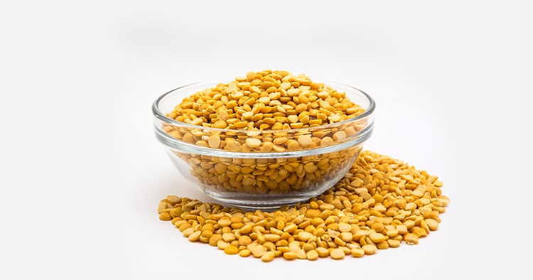 Yellow lentil in glass bowl isolated on white background