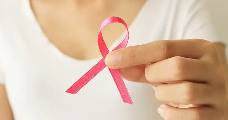 Woman hand holding pink breast cancer awareness ribbon.