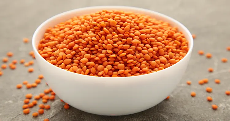 Red lentils in bowl on a grey wooden table. Top view.