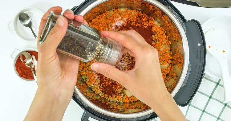Lentil soup recipe, cooking using modern multi cooker. Woman adds black pepper into pot