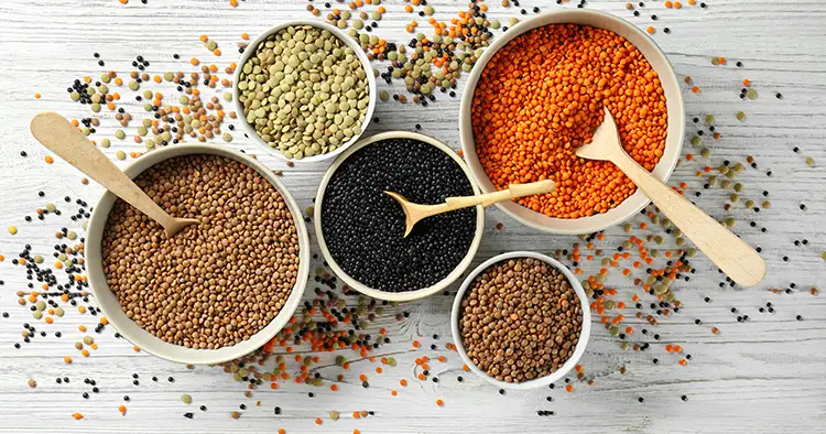 Bowls with different types of lentils on wooden table