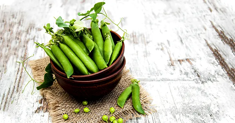 Bowl with fresh peas on a old wooden background