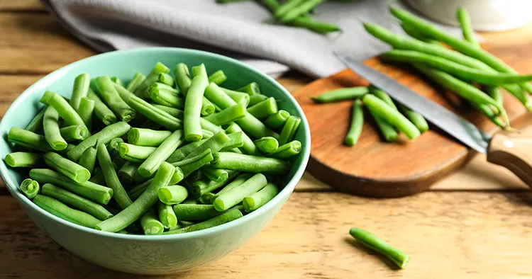 Fresh green beans in bowl on wooden table, closeup