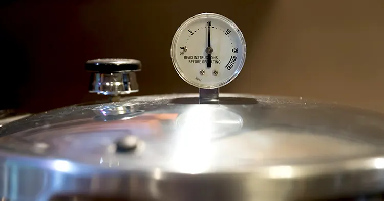 A stainless steel pressure cooker lid with pressure gauge