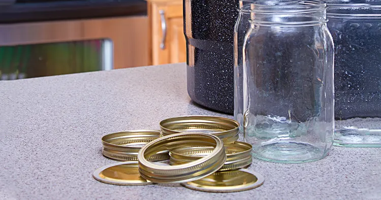 Canning jars with lids, canner or pot in a kitchen setting