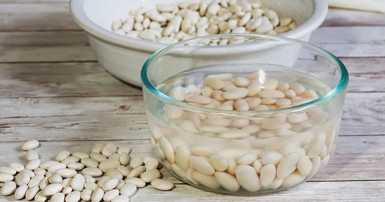 Soaked and dry white navy beans on a wooden tabletop
