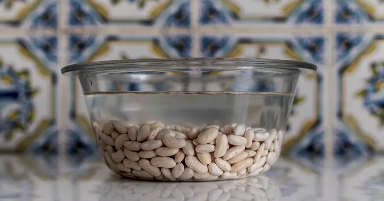 Glass container with white beans to soak. Kitchen with traditional tiles.